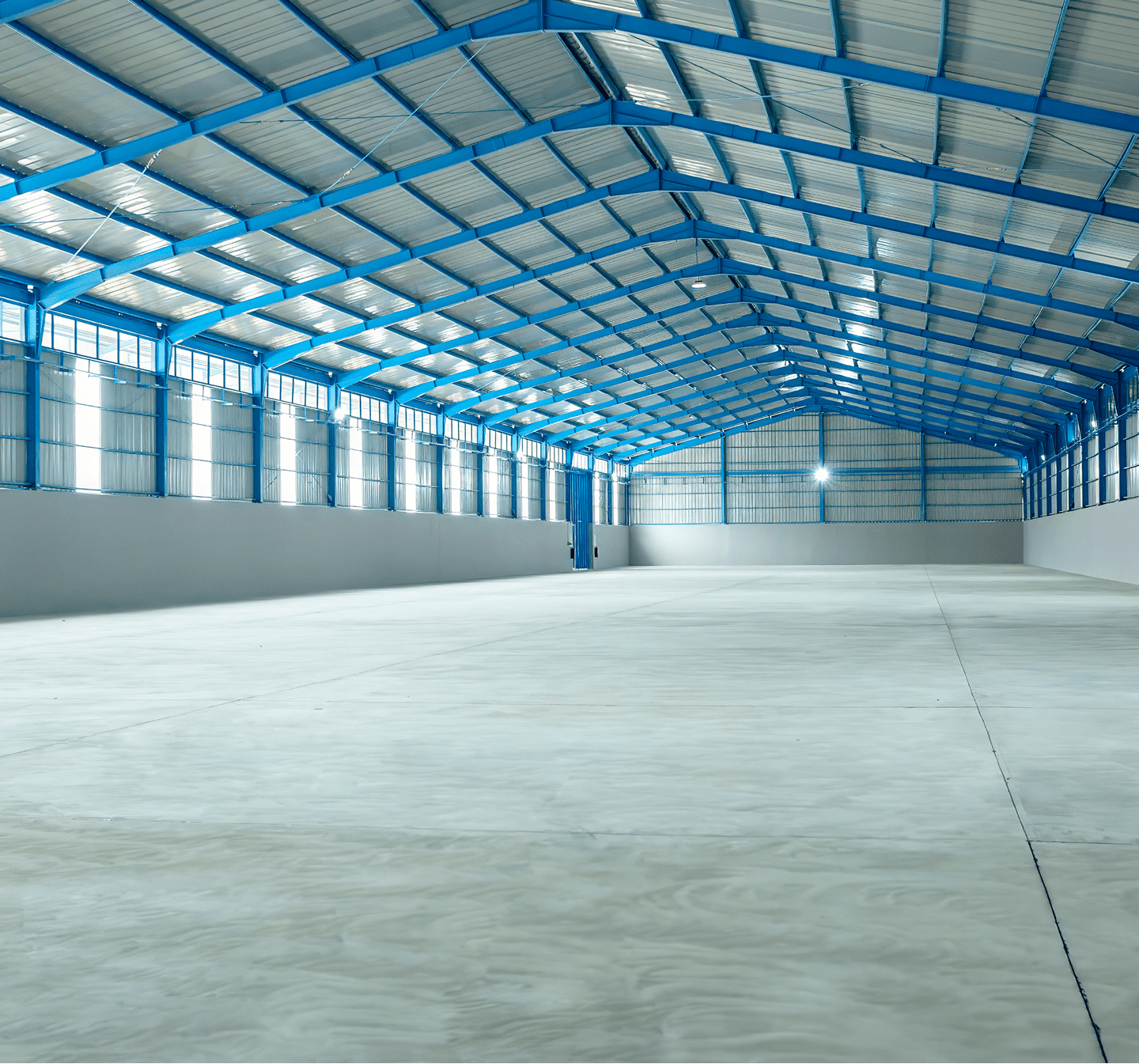 Spacious empty warehouse with blue steel beams.