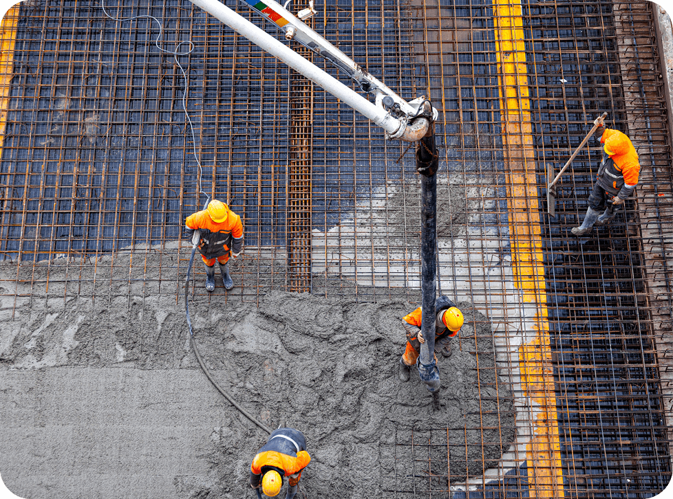 Construction workers pouring concrete on rebar.